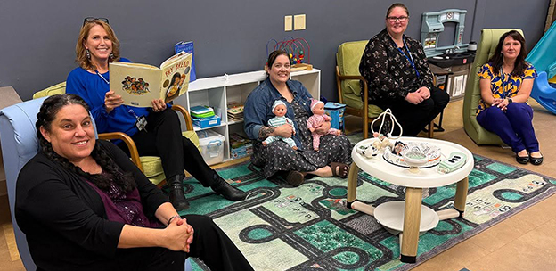 Staff members in the parent teacher lounge space smiling at the camera